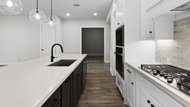 kitchen with stainless steel appliances, white cabinetry, decorative light fixtures, dark hardwood / wood-style flooring, and sink