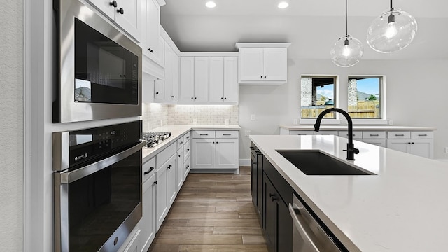 kitchen with white cabinets, appliances with stainless steel finishes, hanging light fixtures, and sink