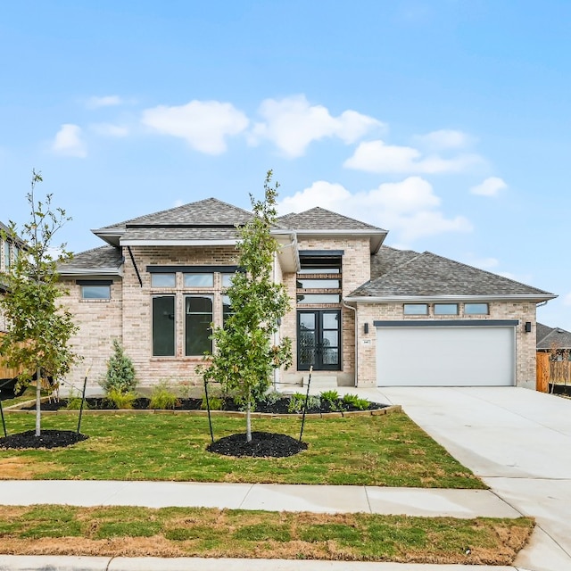 prairie-style home featuring french doors, a garage, and a front lawn