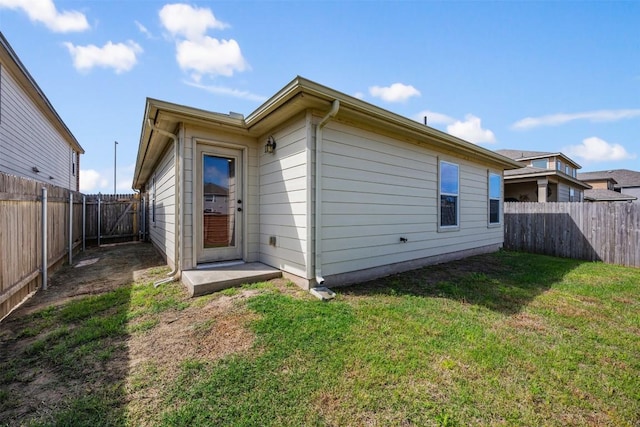 rear view of house with a yard and a fenced backyard