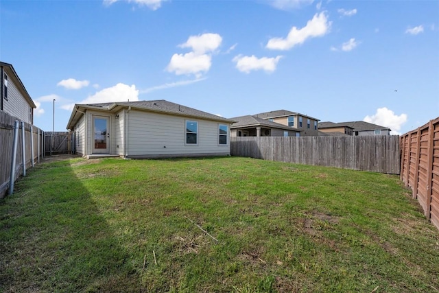 rear view of property featuring a lawn and a fenced backyard