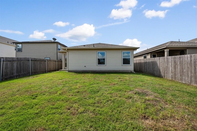 rear view of house with a fenced backyard and a yard