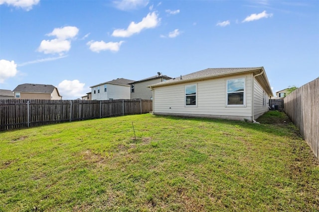 back of house with a yard and a fenced backyard