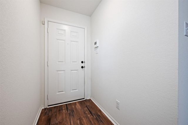 doorway to outside featuring baseboards and dark wood-style flooring