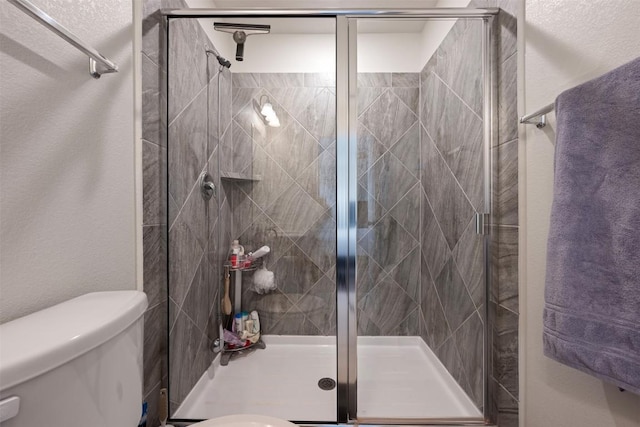 bathroom featuring a stall shower, toilet, and a textured wall