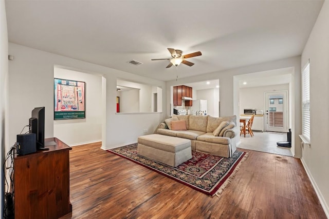 living room featuring visible vents, baseboards, wood finished floors, and a ceiling fan