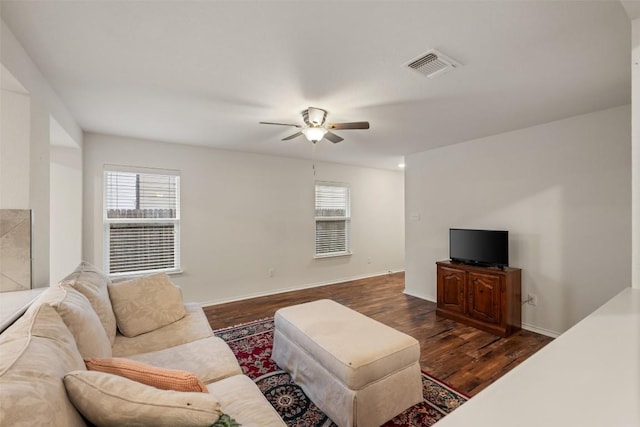 living room with visible vents, baseboards, dark wood-style floors, and a ceiling fan