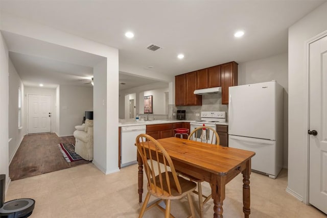 kitchen with visible vents, under cabinet range hood, light countertops, white appliances, and a ceiling fan