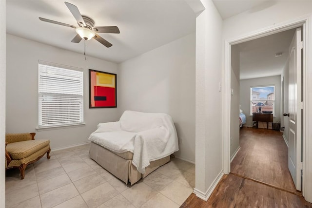 sitting room with baseboards, light wood-style flooring, and a ceiling fan