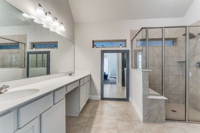 bathroom with a shower with door, dual sinks, large vanity, and tile floors