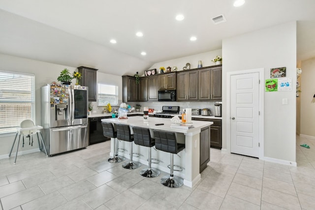 kitchen with a kitchen bar, a kitchen island, black appliances, lofted ceiling, and dark brown cabinetry