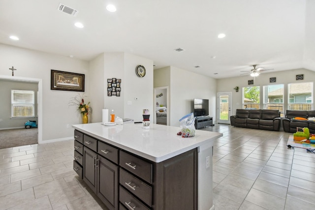 kitchen featuring a center island, ceiling fan, light tile floors, and dark brown cabinetry