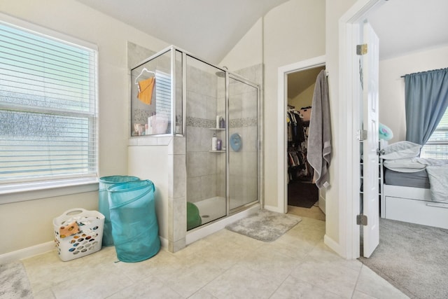 bathroom with a shower with door, vaulted ceiling, and tile floors