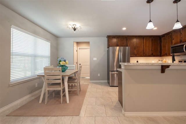 kitchen featuring hanging light fixtures, a wealth of natural light, stainless steel appliances, and light tile floors