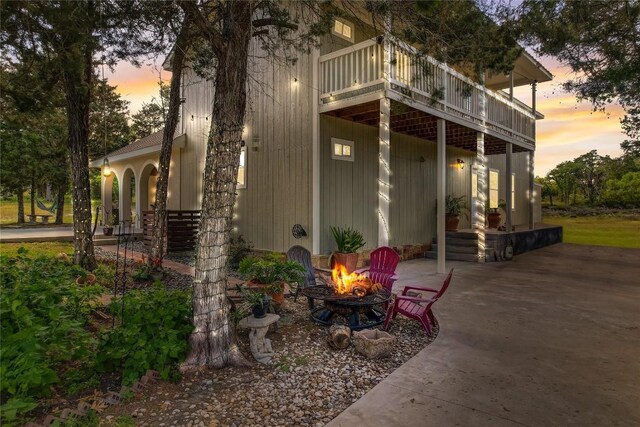 property exterior at dusk featuring a patio and a fire pit