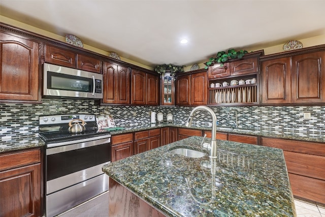 kitchen with dark stone counters, tasteful backsplash, sink, appliances with stainless steel finishes, and light tile patterned floors