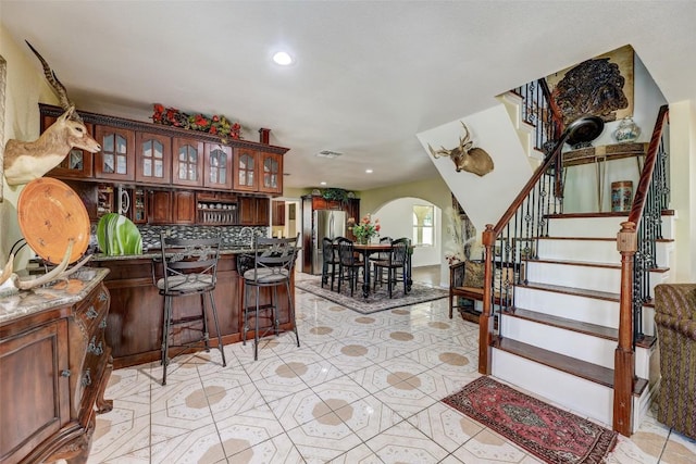 interior space with light tile patterned flooring, stainless steel fridge, and backsplash