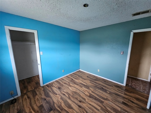 unfurnished bedroom with a closet, dark hardwood / wood-style floors, and a textured ceiling