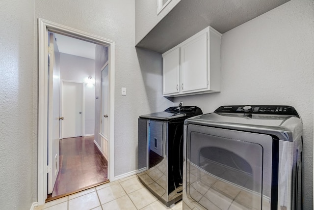 clothes washing area with cabinets, washer and dryer, and light hardwood / wood-style floors