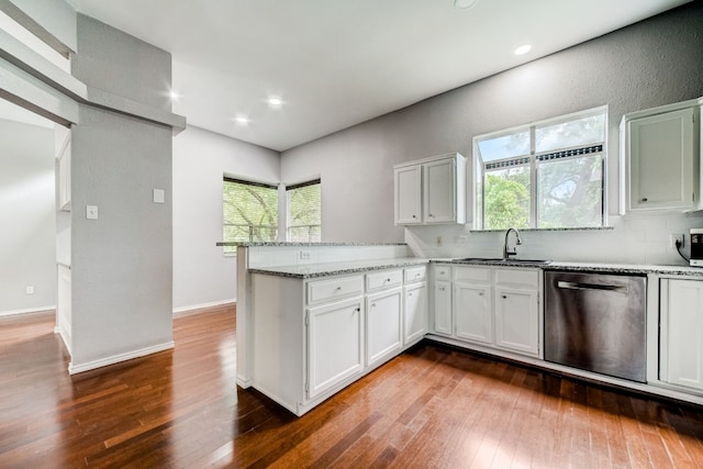 kitchen with dark wood-type flooring, a healthy amount of sunlight, kitchen peninsula, and stainless steel dishwasher