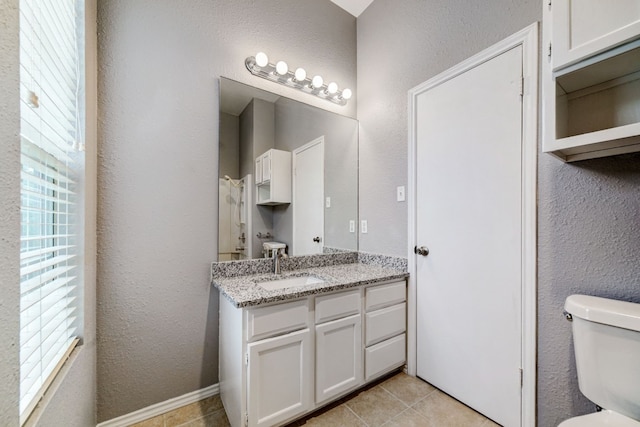 bathroom featuring a healthy amount of sunlight, tile patterned flooring, toilet, and vanity