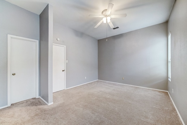 spare room with ceiling fan, a wealth of natural light, and light carpet