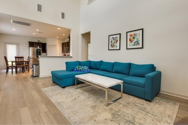 living room with a high ceiling and light wood-type flooring