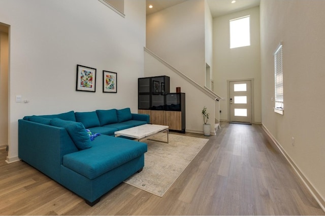 living room with plenty of natural light, a towering ceiling, and light hardwood / wood-style floors