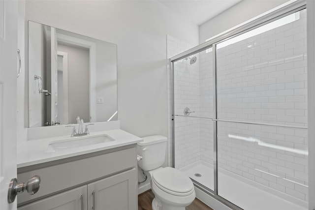 bathroom featuring vanity, hardwood / wood-style flooring, a shower with door, and toilet