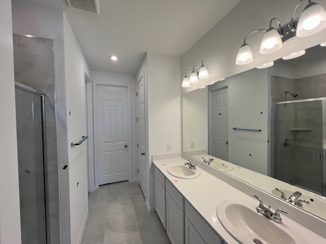 bathroom featuring dual bowl vanity, tile patterned floors, and a shower with shower door