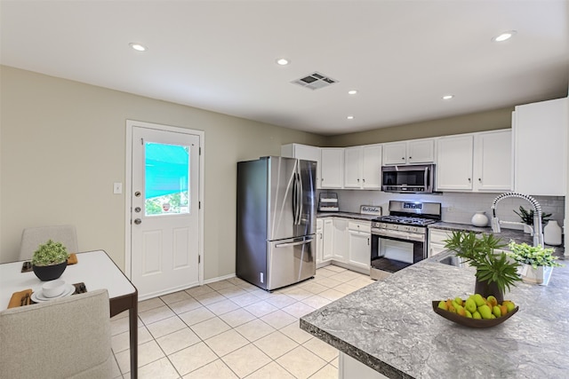 kitchen featuring appliances with stainless steel finishes, backsplash, sink, light tile patterned floors, and white cabinets