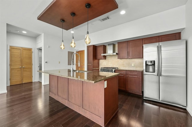 kitchen featuring wall chimney exhaust hood, stainless steel appliances, a kitchen island with sink, and sink