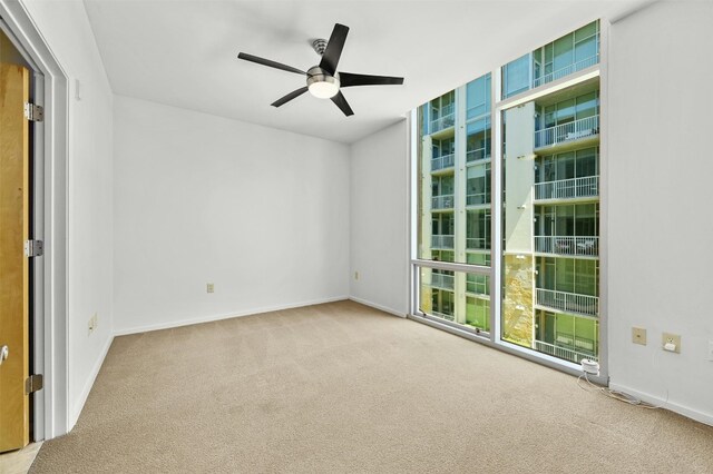 carpeted empty room with floor to ceiling windows and ceiling fan