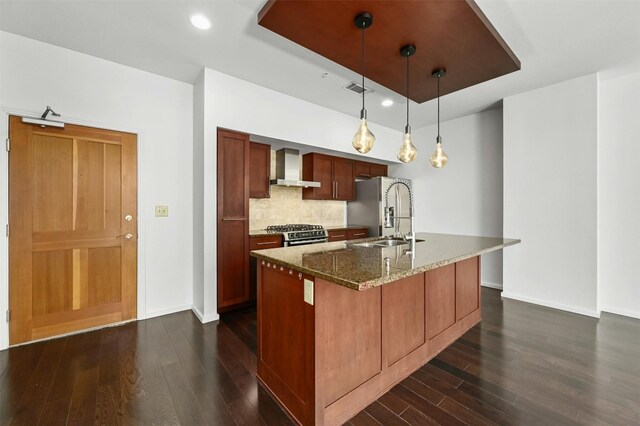 kitchen with wall chimney exhaust hood, stainless steel appliances, decorative light fixtures, dark hardwood / wood-style floors, and sink