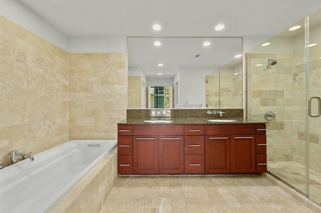 bathroom with tile walls, shower with separate bathtub, and vanity