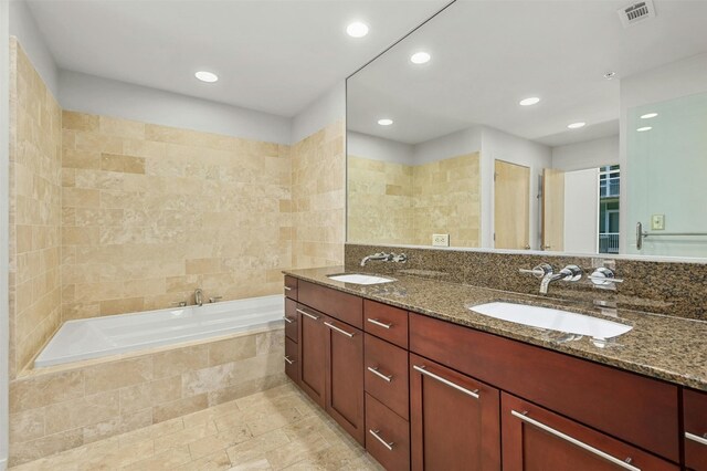 bathroom with vanity and a relaxing tiled tub