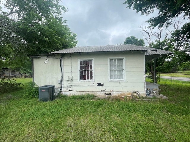 rear view of property featuring a yard and central air condition unit