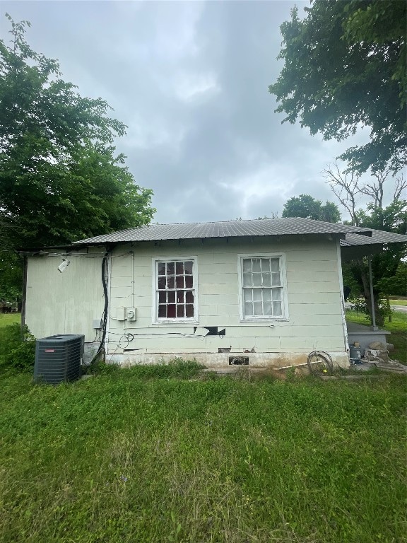 rear view of property featuring central AC and a lawn