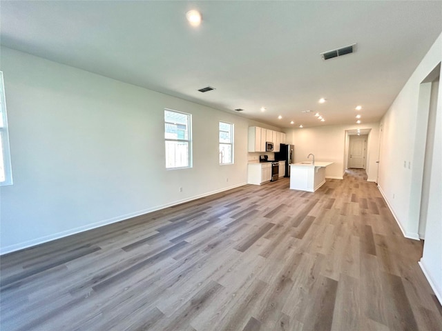 unfurnished living room with light hardwood / wood-style flooring and sink