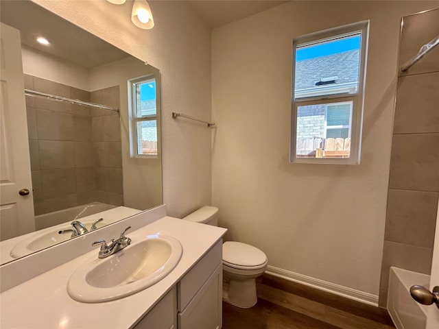 full bathroom featuring vanity, toilet, hardwood / wood-style flooring, and tiled shower / bath