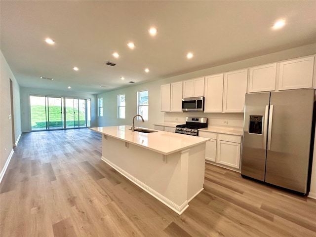 kitchen with a center island with sink, sink, stainless steel appliances, and light hardwood / wood-style floors