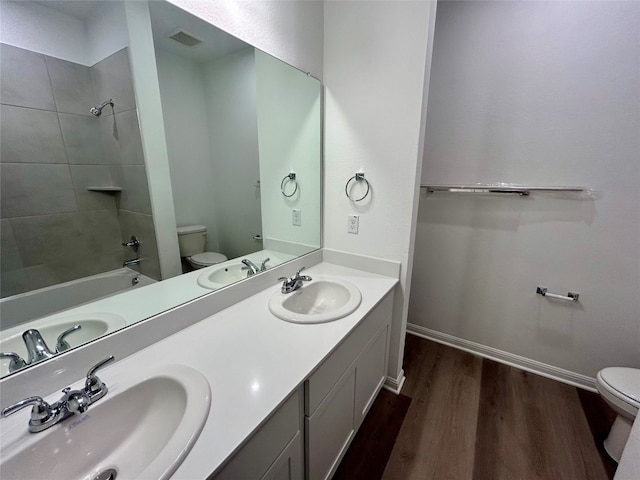 full bathroom featuring vanity, toilet, tiled shower / bath combo, and wood-type flooring