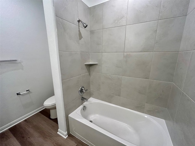 bathroom featuring toilet, tiled shower / bath, and hardwood / wood-style flooring