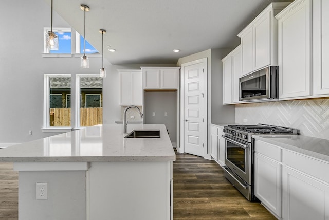 kitchen featuring sink, backsplash, hanging light fixtures, a center island with sink, and appliances with stainless steel finishes