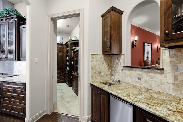 bar featuring arched walkways, a sink, wet bar, and decorative backsplash