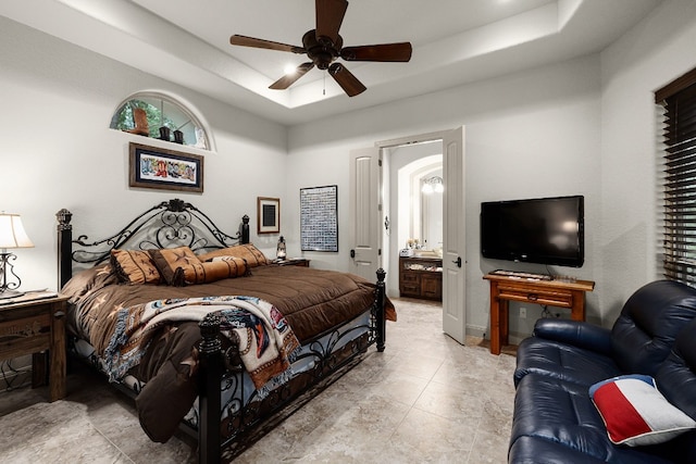 bedroom with a tray ceiling, a ceiling fan, and ensuite bathroom