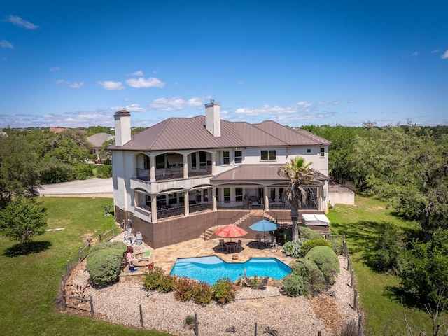 back of property with an outdoor pool, a balcony, metal roof, a standing seam roof, and a patio area