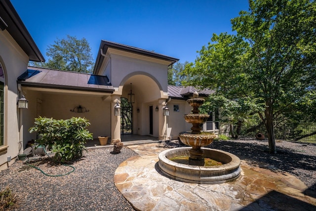 doorway to property featuring metal roof, a standing seam roof, a patio area, and stucco siding