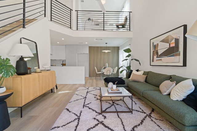 living room with a towering ceiling and light wood-type flooring