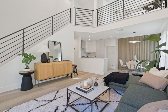 living room with light hardwood / wood-style flooring and a towering ceiling